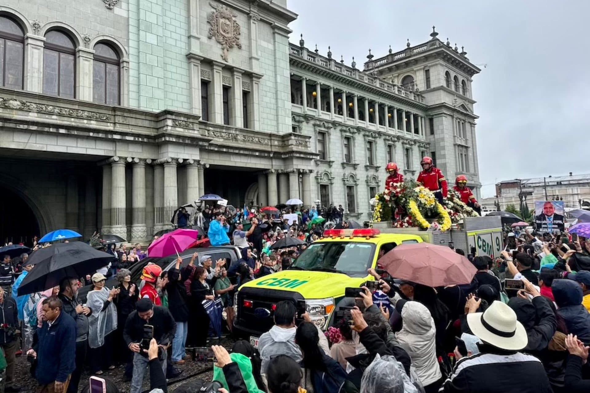 El vehículo de los bomberos, con el féretro y arreglos florales, avanza entre la multitud frente al Palacio Nacional.
